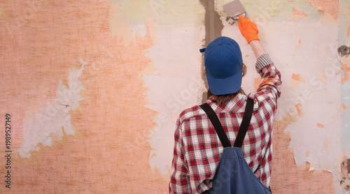 Construction worker removing old wallpaper from wall in apartment. concept of home renovation. copy space