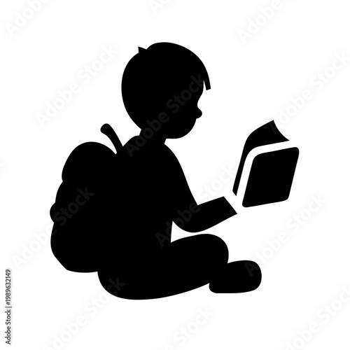 Silhouette of a school child sitting and reading a book