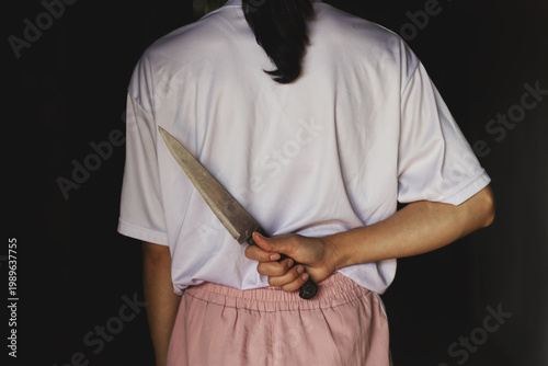 Silent Threat: Woman Concealing a Large Knife Behind Her Back
