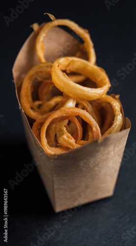 Golden crispy onion rings served in a paper container, perfect for a delicious snack.