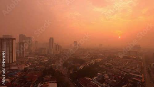 A hazy sunset over a bustling cityscape, showcasing tall buildings and urban life in warm hues.