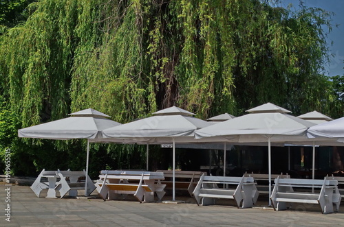 Relaxation corner under canopies with tables and benches on the shore of Lake Ariana, Sofia, Bulgaria
