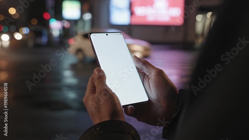 Person holding smartphone with white screen at nighttime in city
