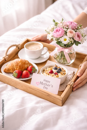 Close-up of hands serving breakfast tray with coffee, flowers and card, Mother’s Day surprise concept, soft natural light, cozy scene.