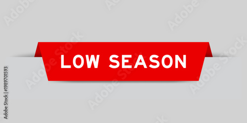 Red color inserted label with word low season on gray background
