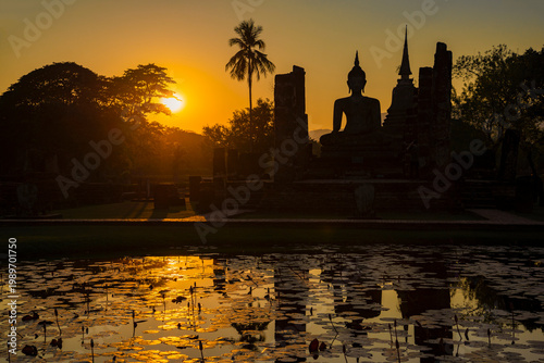 Silhouette of Buddha against the background of evening sunset. Ruins of the ancient Buddhist temple Wat Chana Songkhram. Sukhothai Historical Park. Thailand