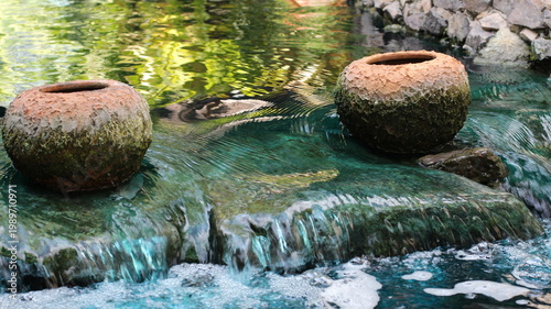 Bild auf Leinwand Serene garden pond with two rustic clay pots and shimmering water