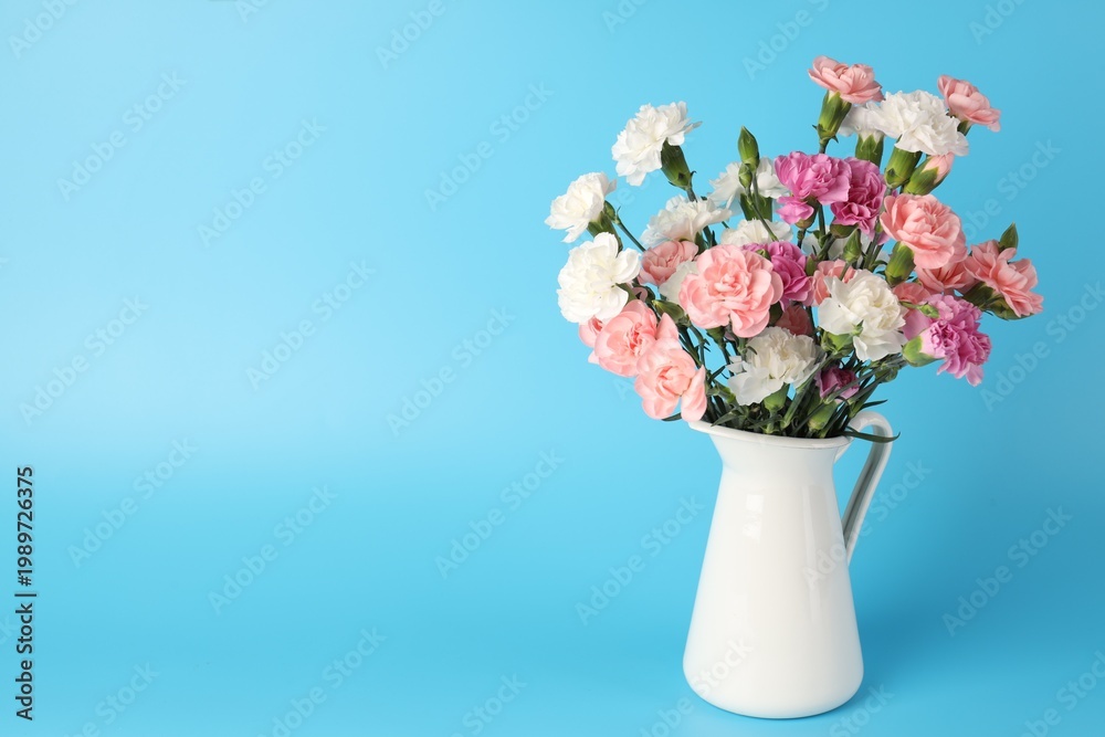 Obraz premium Beautiful carnation flowers in vase on light blue background, space for text