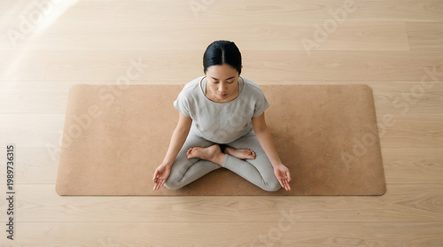 A person seated in meditation position on a yoga mat bright light