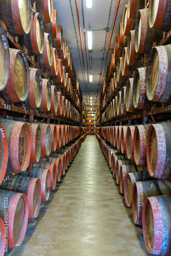 Long rows of traditional oak barrels, stacked high in the aging cellars of the historic Rum Distillery, mature under controlled conditions in the town of Arucas
