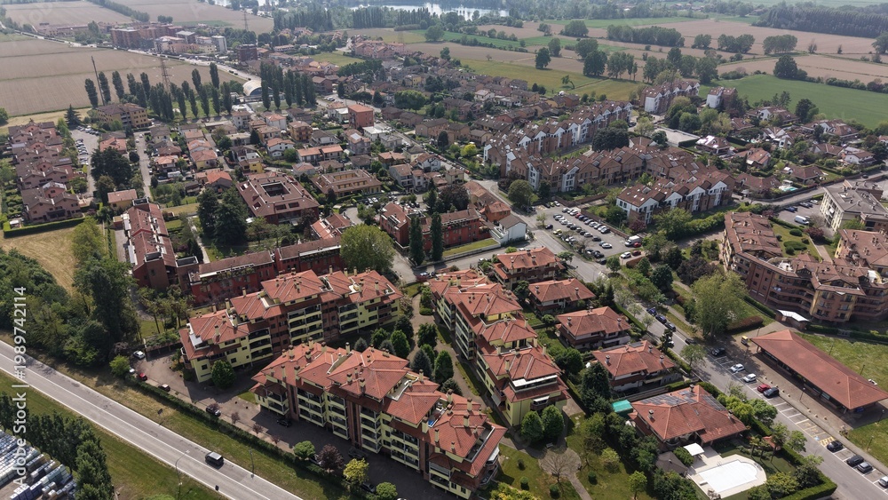 Obraz premium Aerial View of a Suburban Neighborhood: An expansive aerial perspective showcases a vibrant suburban neighborhood with tightly packed residential buildings featuring terracotta roofs.