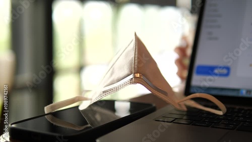 Close-up of N95 face mask on a laptop and smartphone for PM 2.5 dust protection, healthcare, and urban lifestyle concept