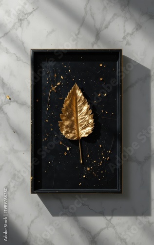 Golden leaf with gold splatter on black background art piece with marble texture
