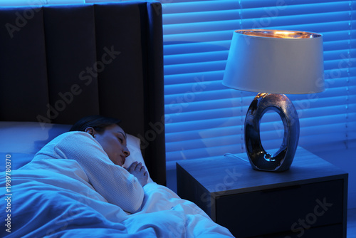 Fotografie Woman sleeping with illuminated night lamp at home