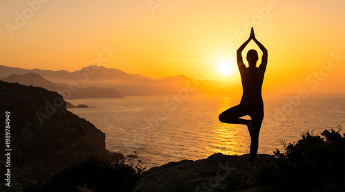 A serene woman practicing yoga on a rocky cliff overlooking a peaceful ocean at sunset