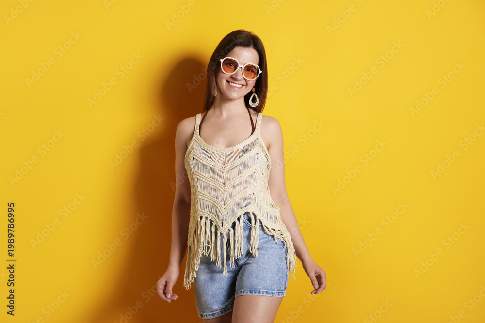 Fototapeta premium Beautiful woman in stylish beachwear on yellow background