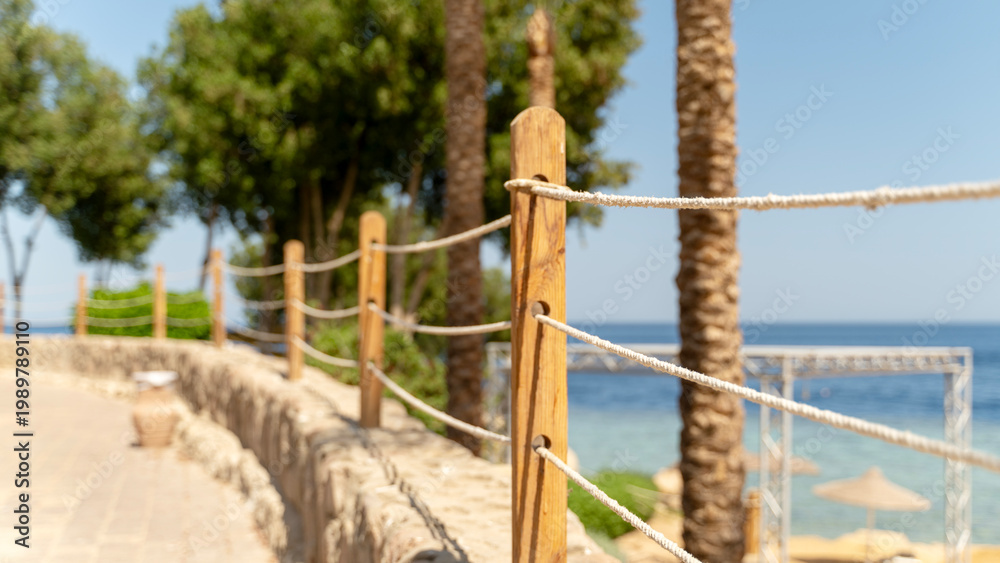 Fototapeta premium Sunlit path winds past rope fencing