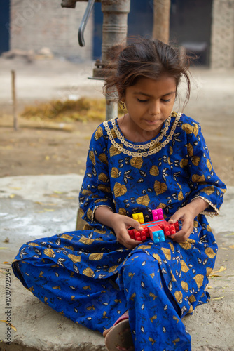 Foto Little girl playing with toy while sitting on ground in rural village simple chi