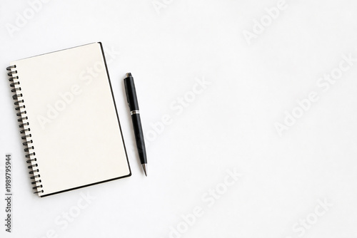 Notebook and Pen: A classic spiral-bound notebook lies open beside a sleek, black pen, offering a blank canvas for ideas and thoughts, evoking a sense of productivity and focus.
