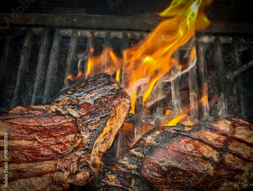 Two sirloin steaks grilling on barbecue with flames and smoke, close up of beef steaks cooking over open fire, juicy meat searing on grill, outdoor BBQ food preparation