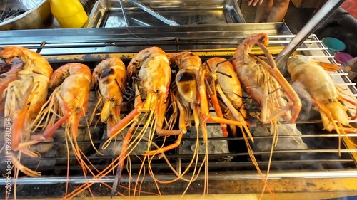 A street food market in a rural Thai town sells medium-sized grilled river prawns to tourists.