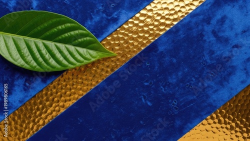 A vibrant green leaf on a textured blue and gold background