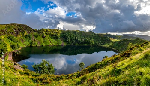 Calm lake reflection amidst vibrant green hills under a dramatic cloudy sky