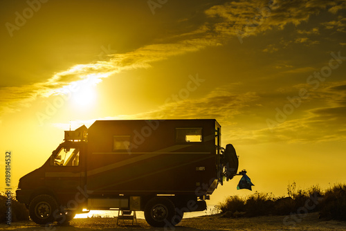 Lorry motorhome with equipment camping on beach at sunrise
