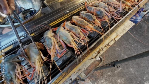 A street food market in a rural Thai town sells medium-sized grilled river prawns to tourists.