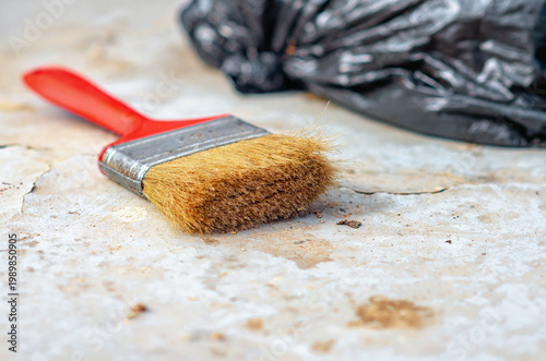 Paint brush with orange handle lying on old wooden board. Concept of repair, painting and DIY work.