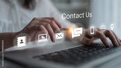 Tableau sur toile A close-up view of hands typing on a laptop keyboard with contact us icons displayed prominently, representing modern customer engagement and digital communication
