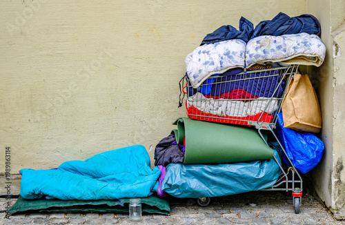 Quadro su tela Stacked blankets and bedding in a shopping cart near a wall in an urban area dur