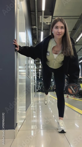 Russia, Izhevsk, April 16, 2026, fitness center. Young woman exercising in gym while stretching and holding dumbbell  