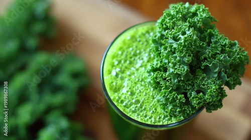 Glass containing freshly blended green liquid beverage garnished with leafy vegetable on wooden surface
