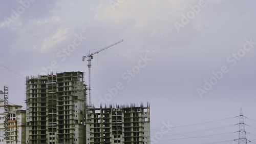 Timelapse Tower crane above unfinished high-rise buildings in Delhi under cloudy sky, representing urban growth, real estate development and construction industry progress.