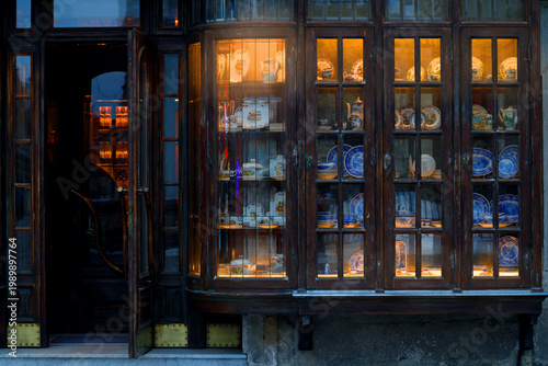 Antique shop display window filled with vintage porcelain and ceramic tableware