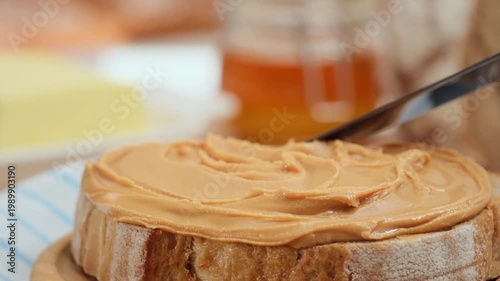 Peanut butter spread on fresh bread slice, homemade breakfast preparation, copy space