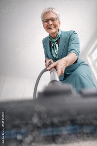 Lächelnde Seniorin beim Staubsaugen