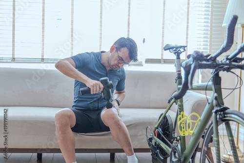 Young Male Athlete Using Percussion Massage Gun on Calf Muscle for Recovery After Indoor Cycling