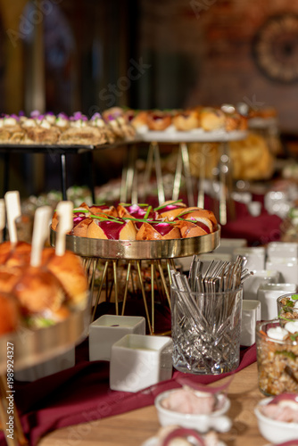 Elegant catering display with gourmet sliders and appetizers on tiered trays, warm lighting, and a refined event atmosphere.