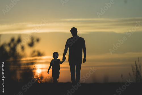 Silhouette of Adult and Child Walking Together at Sunset in Warm Golden Light