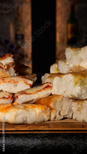 Stacked slices of cheesy pizza focaccia with tomato sauce, golden crust and melted cheese, warm and appetizing comfort food close-up.