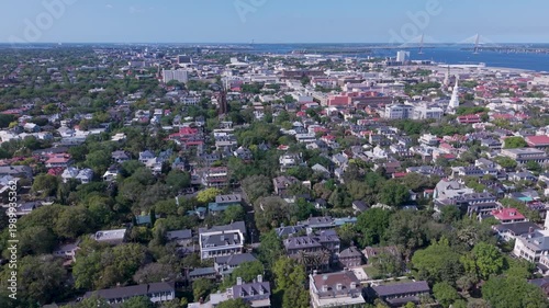 Aerial - Flying over the residential area at the south end of the Charleston, SC peninsula toward the historic town center with harbor and Cooper River Bridge in the distance