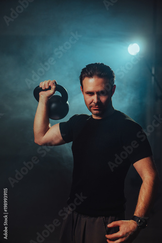 Man holding kettlebell in studio light
