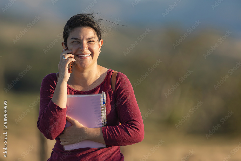 Fototapeta premium Young woman smiling talking on smartphone outdoors