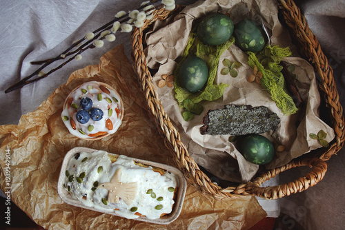 Easter cakes decorated with cream, berries, and seed decoration, pussy willow twigs, colored green eggs