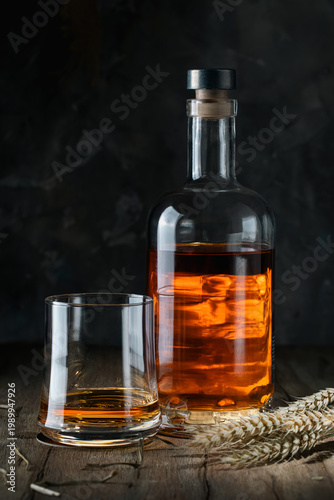 Bottle and glass with alcoholic liquid on a rustic wooden table