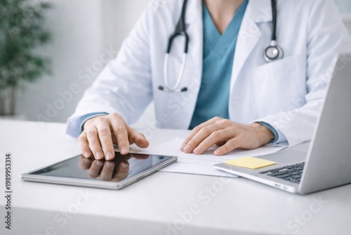 Doctor working at desk with tablet and laptop