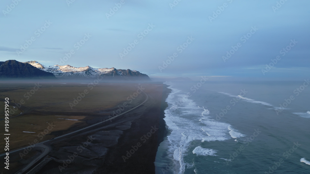 Fototapeta premium Atlanic shore black sand beach, waves crashing on nordic coastline creating natural landscape in iceland. Aerial view of beautiful icelandic scenery and arctic panoramic view. Slow motion.