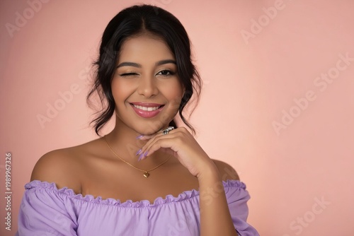 Woman smiles and winks while posing with a playful expression in a studio setting during the morning